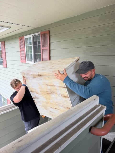 Two Summit crew members carrying a cabinet out of a home